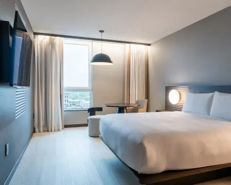Bright and modern hotel guest room with king-size bed, work table, and large window at Burlington Square