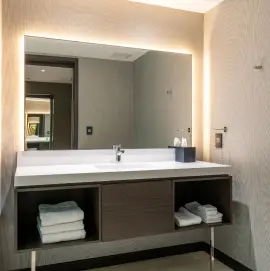 Modern bathroom vanity with illuminated mirror, open shelving, and contemporary finishes at Burlington Square