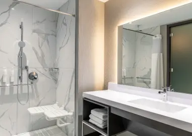 Modern bathroom with walk-in shower, marble-style walls, and spacious vanity at Burlington Square