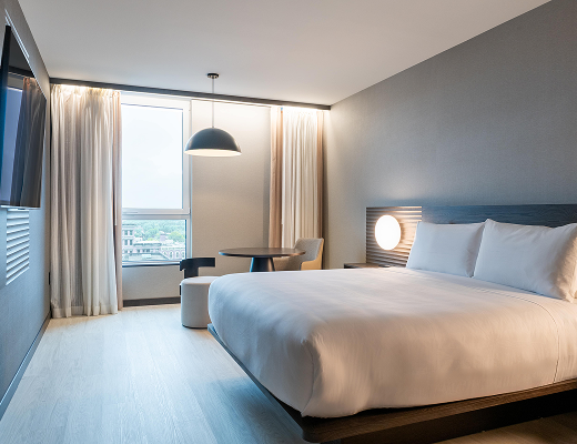 Spacious king guest room at AC Hotel Burlington with city views, modern furnishings, and floor-to-ceiling windows